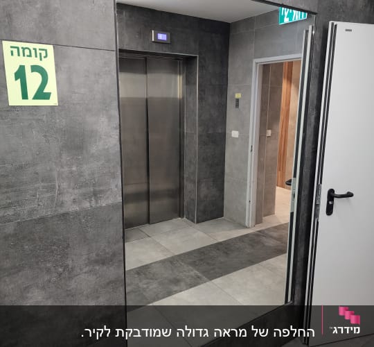 מראה גדולה המותקנת על קיר אריחים בלובי קומה